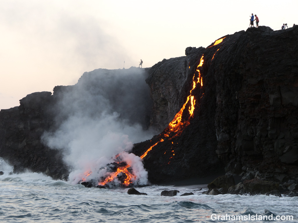 Kilauea lava pours into ocean as people watch from the cliff