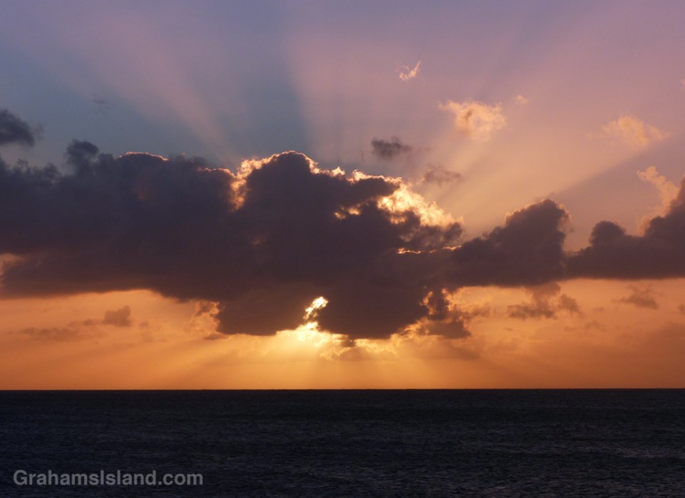A dark cloud blankets the sun approaching sunset.