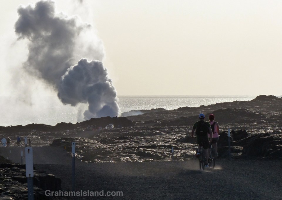 Cyclists head to the Kilauea lava flow where it enters the sea.