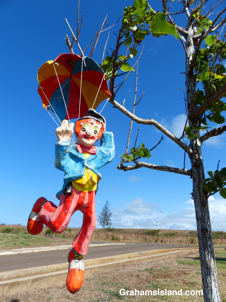 A parachuting clown hangs from a tree.