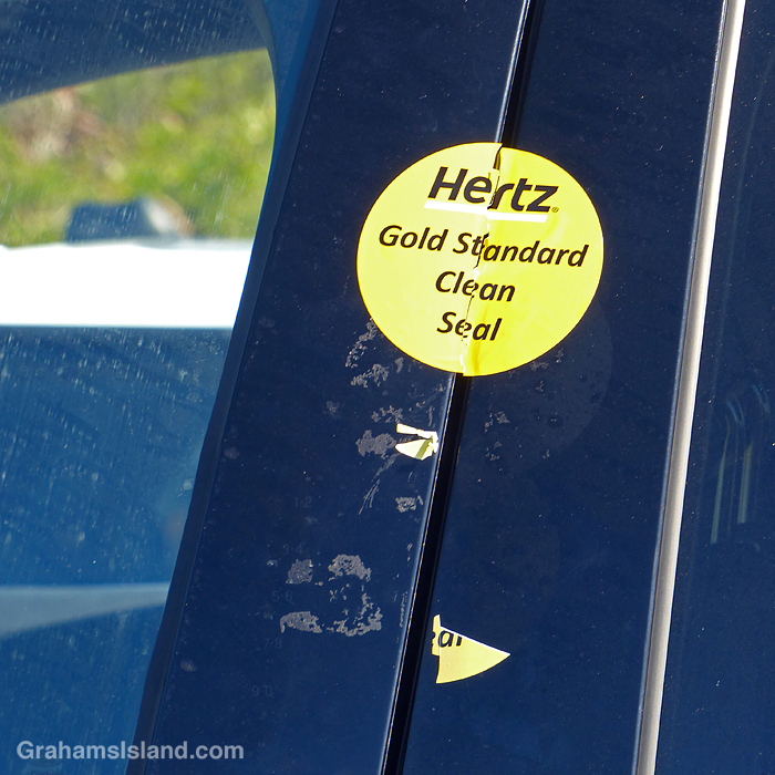 A Hertz Gold Standard Clean Seal sticker on a car