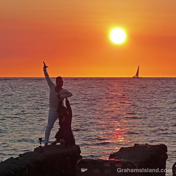 A couple performs on the beach at sunset in Hawaii