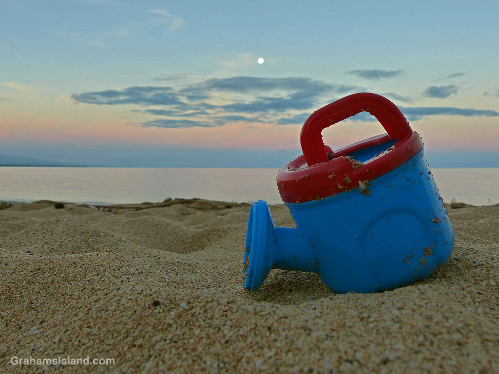 A toy watering can left on a beach in Hawaii