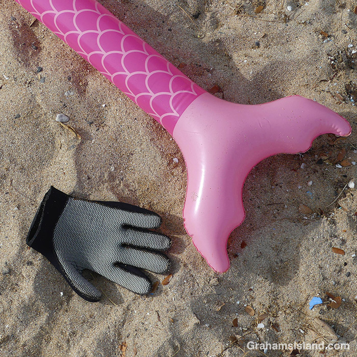 An inflatable mermaid and a glove on a beach in Hawaii