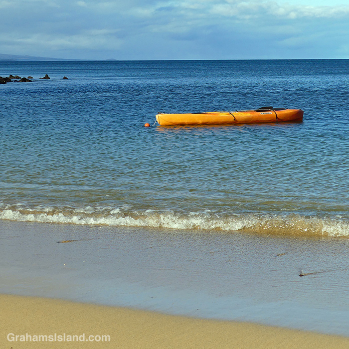 An orange kayak waits on the waters off Spencer Beach Park