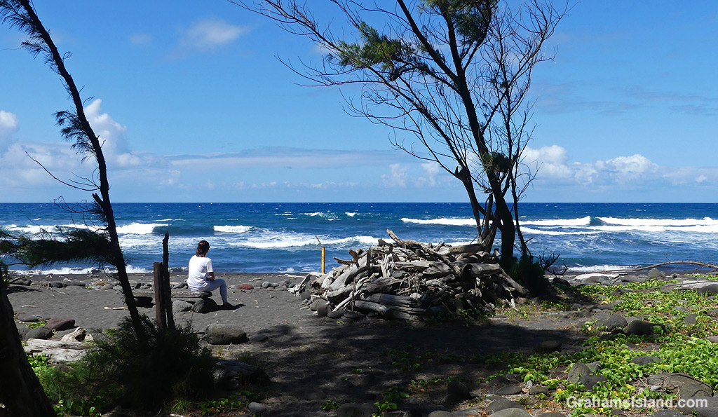 A woman sits on a makeshift bench at Pololu in Hawaii