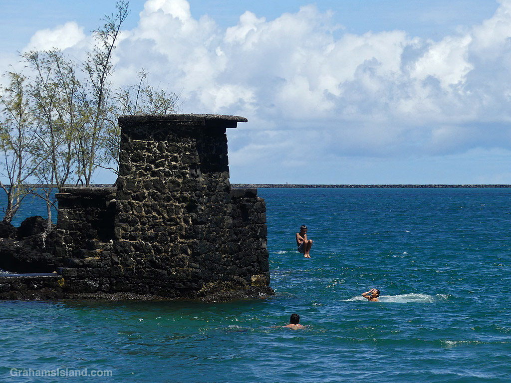 A child jumps into the ocean from a rock tower at Coconut Island, Hilo, Hawaii