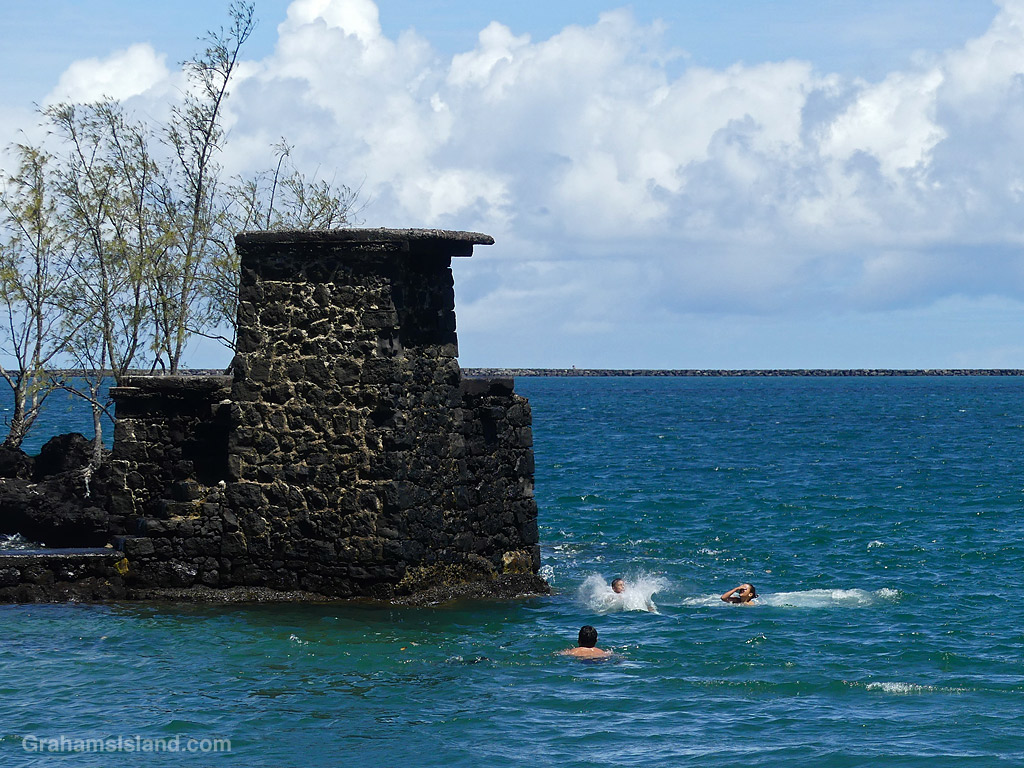 A child jumps into the ocean from a rock tower at Coconut Island, Hilo, Hawaii