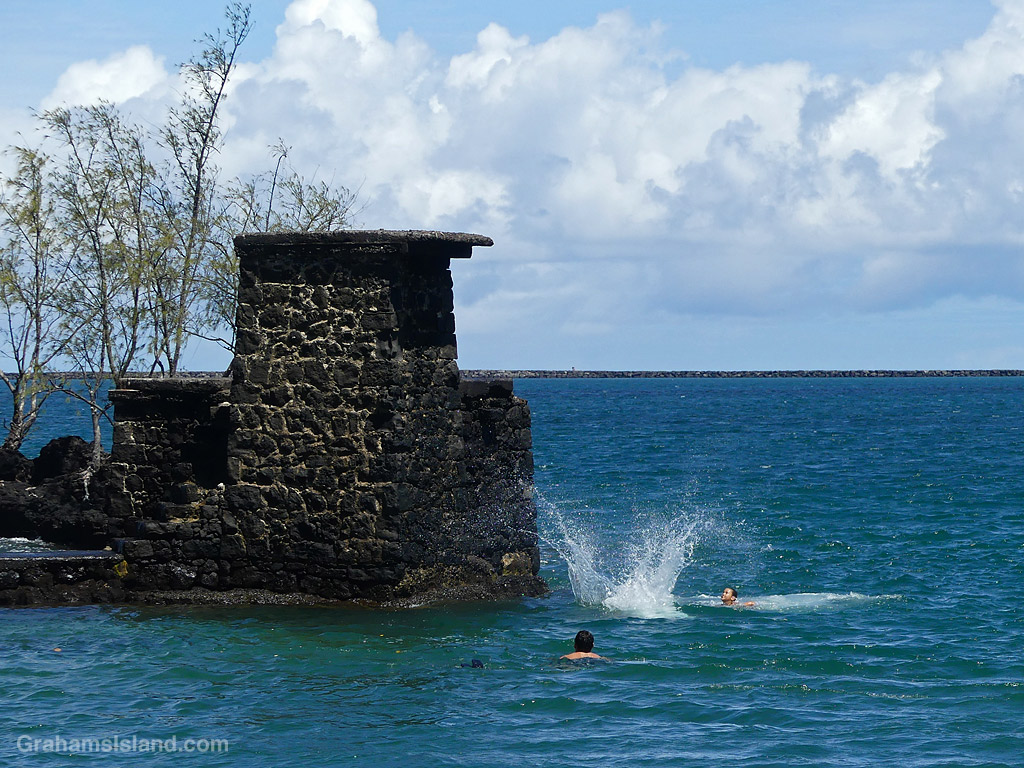 A child jumps into the ocean from a rock tower at Coconut Island, Hilo, Hawaii