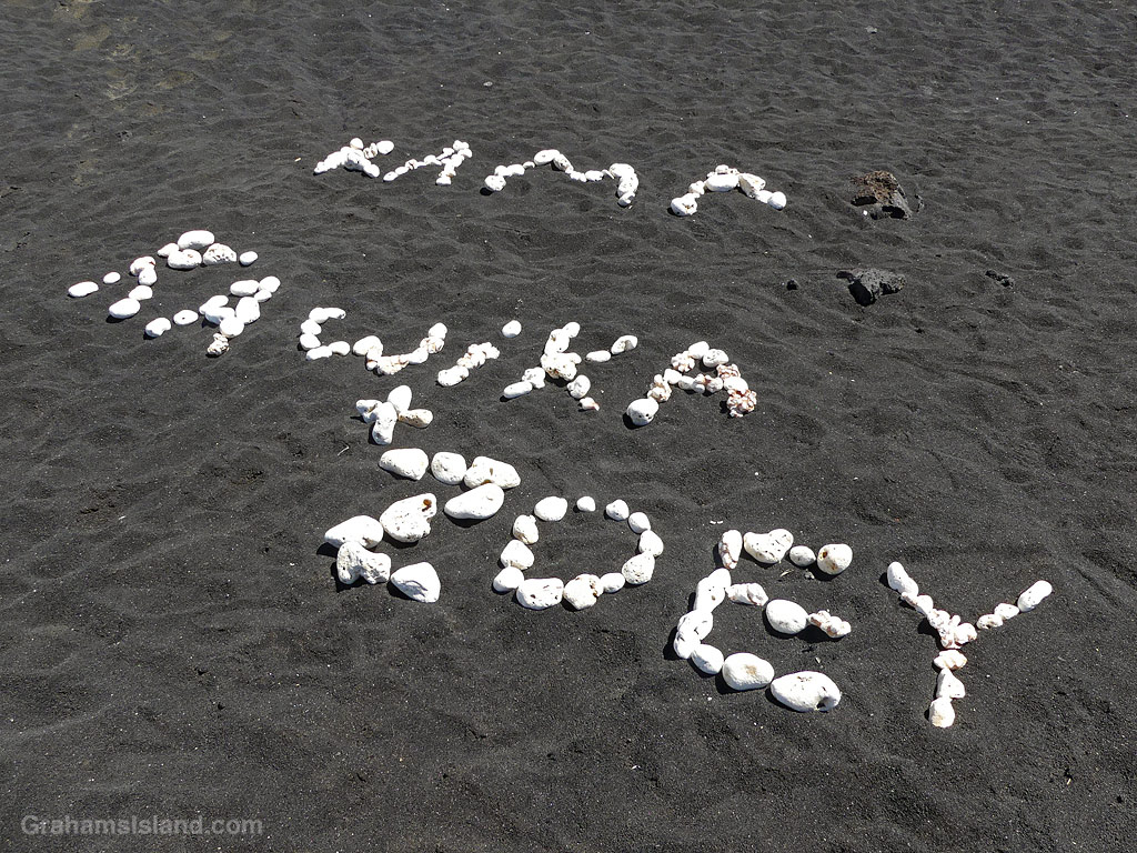 White coral words on a black sand beach in Hawaii