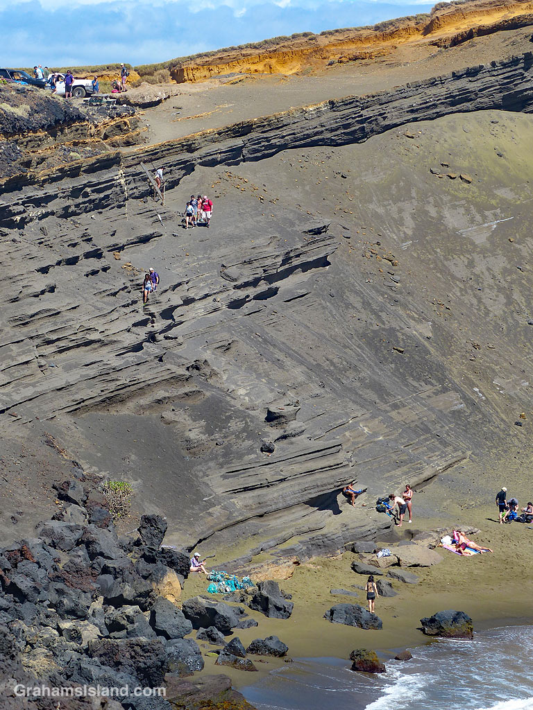People descend to the green sand beach near South Point in Hawaii