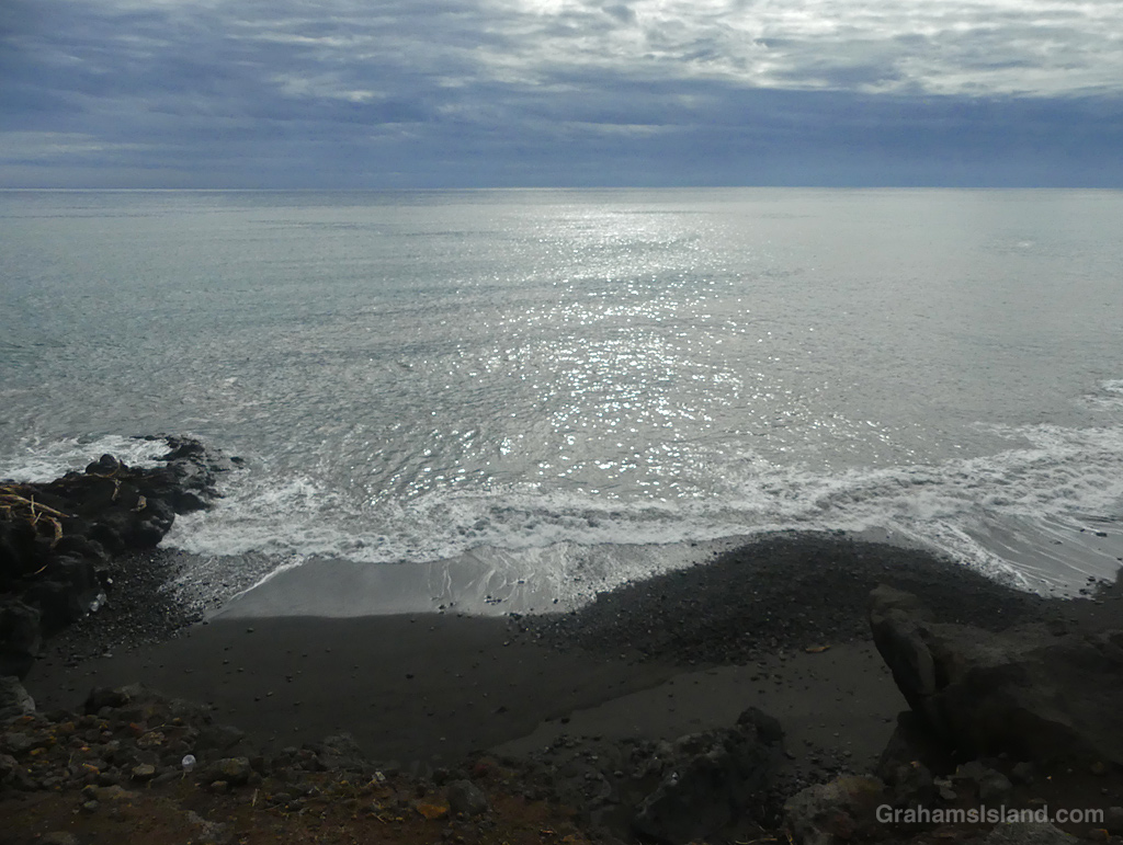 A moody sky above a sparkling sea and small beach at Kawaihae, Hawaii