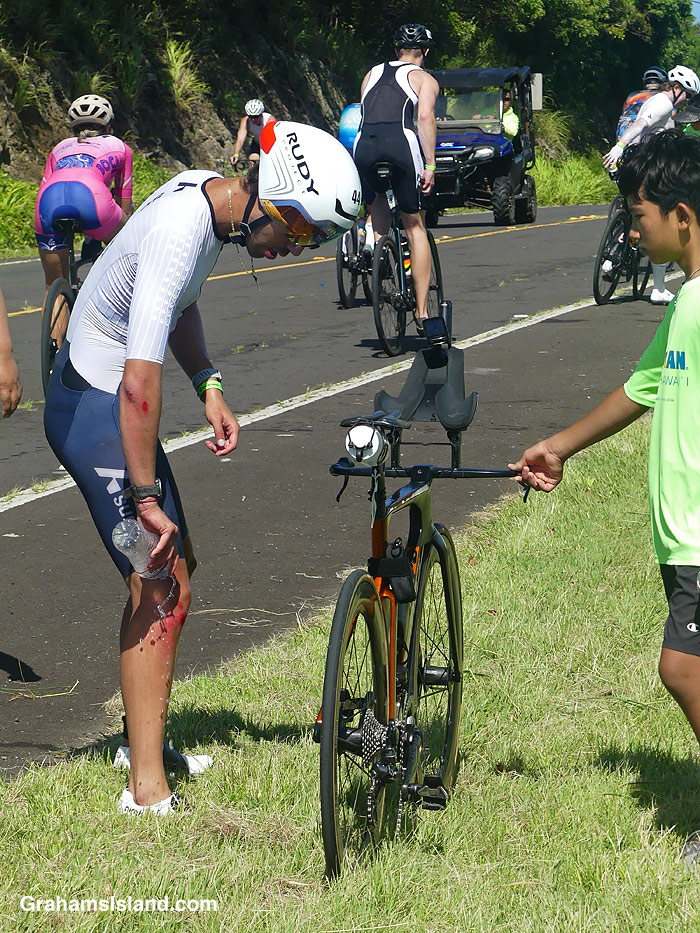 A cyclist in the 2026 Ironman 70.3 race in Hawaii, pours water on himself after he hit a pothole and crashed