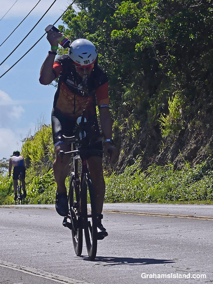 A cyclist in the 2026 Ironman 70.3 race in Hawaii, pours water on himself