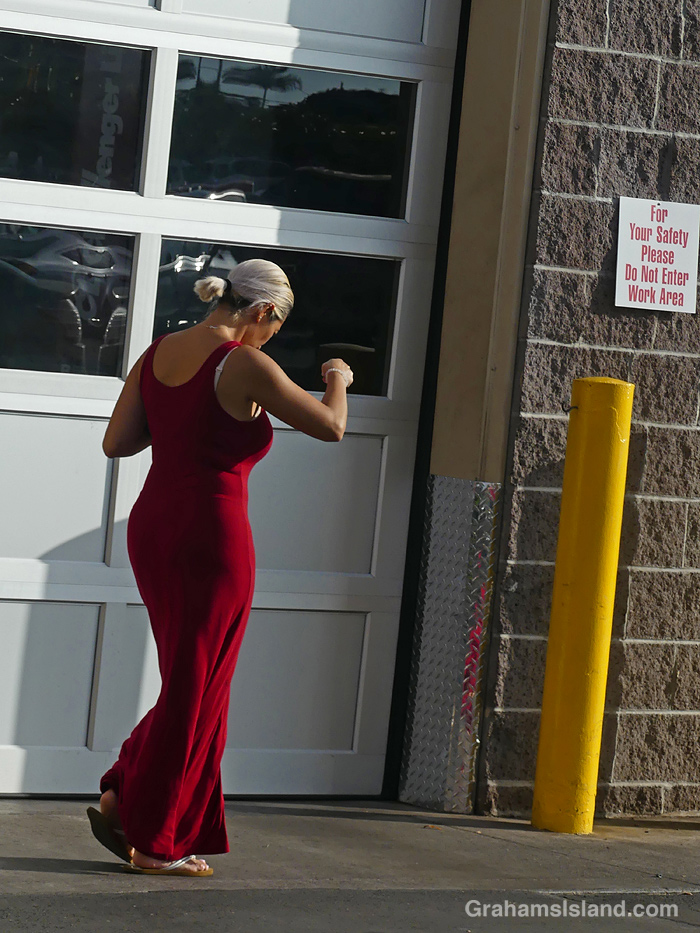 A woman in a red dress walks by Costco Tire center in Hawaii