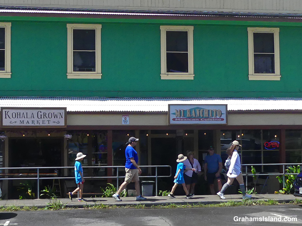 A family of four walks past a building in Hawi, Hawaii